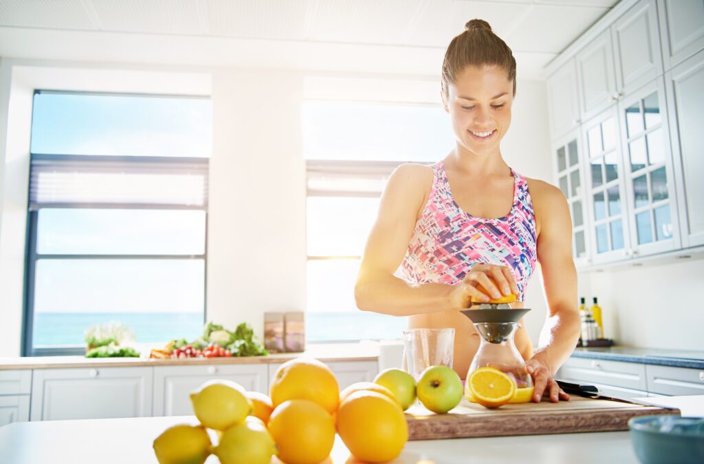 Woman preparing a healthy smoothie in a kitchen as part of healthy lifestyle tips for office professionals.