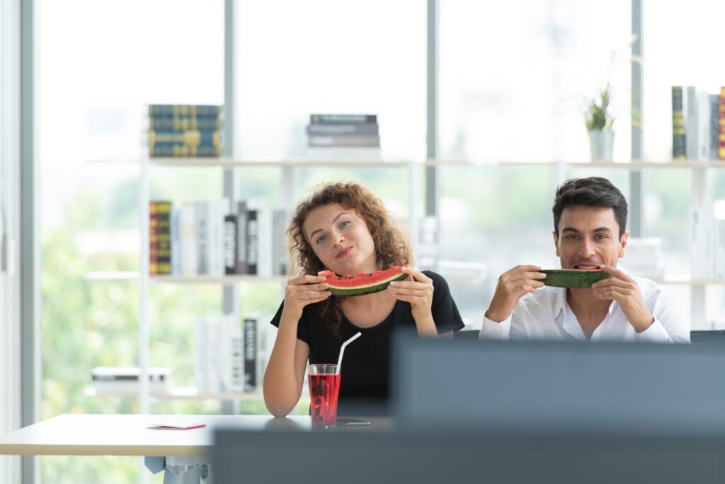 Office workers eating watermelon, following healthy lifestyle tips for office workers for staying energised during the workday.