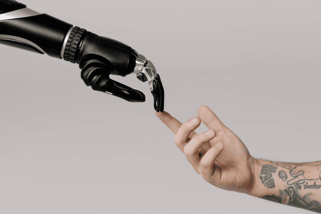 Recruitment trends 2025 - AI and human touch. Photo of an AI robot touching fingers with a human hand. 