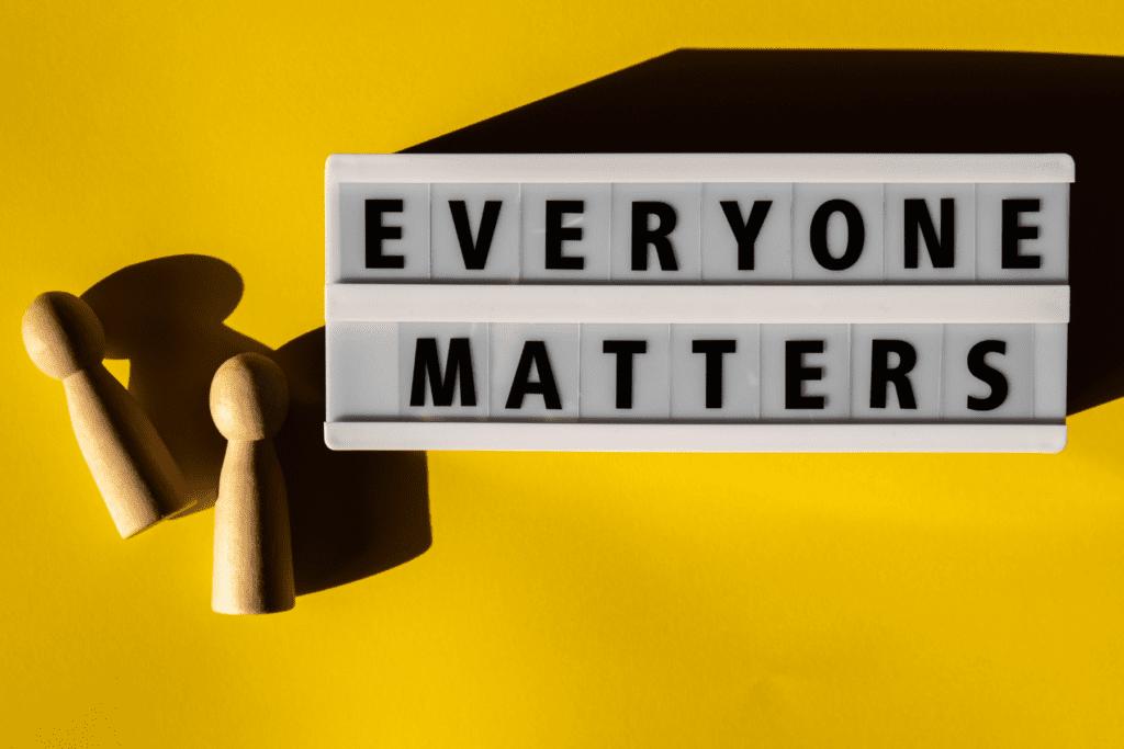 A lightbox sign displaying the words 'Everyone Matters' with two wooden figures on a bright yellow background, symbolising diversity and inclusion in recruitment trends for 2025.