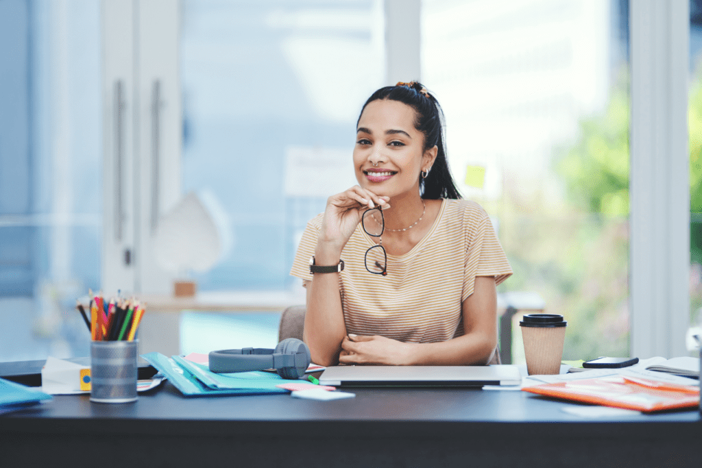 A smiling young professional at a modern desk, symbolising the importance of showcasing company culture and values in employer branding for 2025 recruitment.